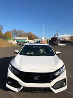 the front end of a white car parked in a parking lot