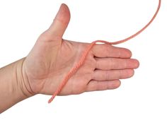 a hand holding an orange string in it's right hand and pointing at the camera