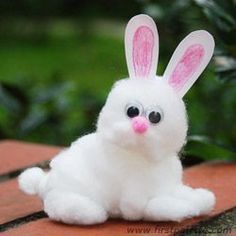 a white stuffed rabbit sitting on top of a wooden table