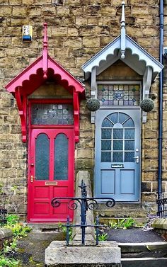 two doors are painted red and blue in front of a brick building