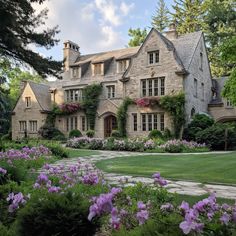 a large house with many windows and flowers in the front yard