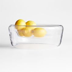 a glass bowl filled with lemons on top of a table