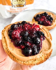 a person holding up a pastry with blueberries and peanut butter on it in their hand