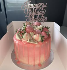 a birthday cake decorated with strawberries and chocolates on a plate in a box