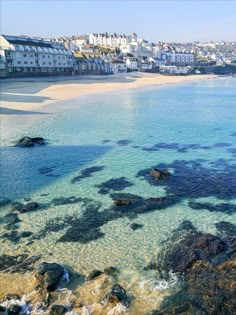 the water is crystal clear and blue with rocks in front of it that are surrounded by buildings