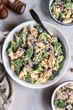 two white bowls filled with pasta and broccoli