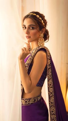 a woman wearing a purple sari and gold jewelry