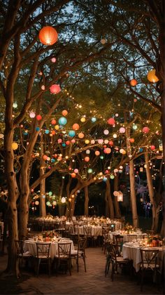 an outdoor dining area with paper lanterns hanging from the trees