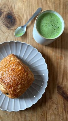 a pastry on a plate next to a cup of green tea