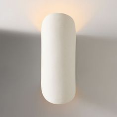 a white cylindrical light fixture mounted on a wall