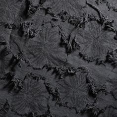 an image of black fabric textured with frayed up stitches and criss cross stitchs