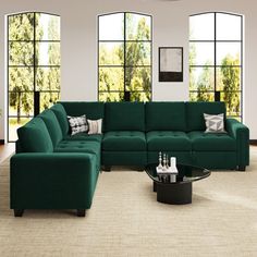 a living room filled with green couches next to large windows and rugs on the floor