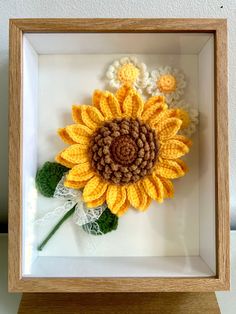 a crocheted sunflower in a wooden frame