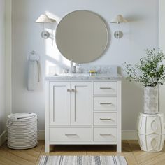 a white bathroom vanity with a round mirror above it and a rug on the floor