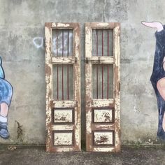 two wooden doors are painted on the side of a building