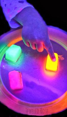 a person pointing at some glowing objects on a table with their finger in the middle