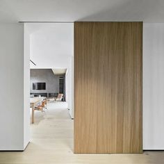 an open door leading to a dining room and living room with white walls, wood flooring and wooden furniture