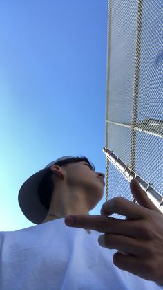 a person standing next to a fence with their hand on the side of the fence