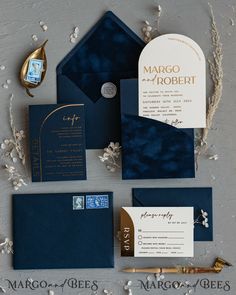 the wedding stationery is laid out on top of each other, including blue and gold