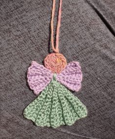 a crocheted angel ornament hanging from a string on a gray shirt