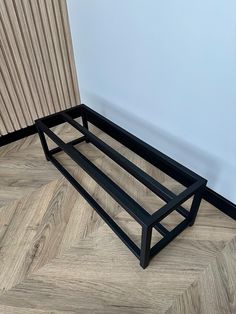 a black metal shelf sitting on top of a wooden floor