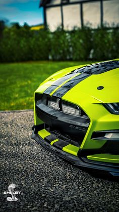 the front end of a lime green sports car parked on top of a gravel road