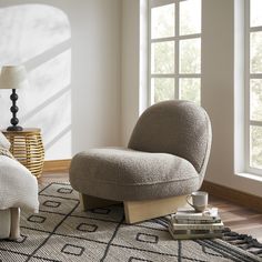 a living room with a chair and rug in front of a window on the floor