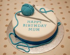 a birthday cake with a knitting needle and ball of yarn