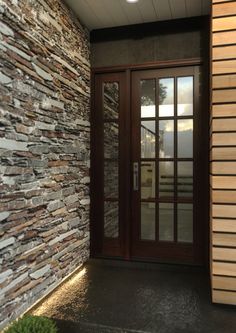 an entrance to a building with stone walls and glass doors