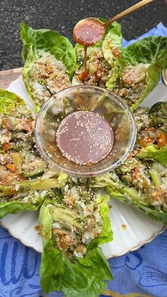 lettuce wraps with dipping sauce on a white plate and blue table cloth, ready to be eaten