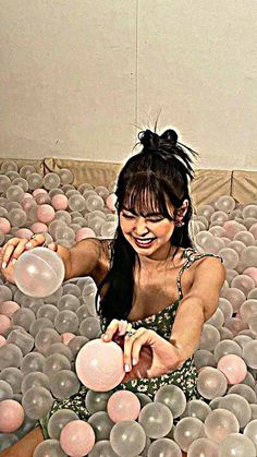 a woman in a ball pit with lots of balls around her and one hand reaching out to grab something