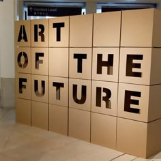 the words art of the future are cut out of cardboard boxes on display in an office building