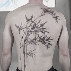 a man with a tattoo on his back is standing in front of a mirror and looking at the bamboo tree