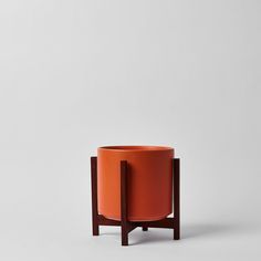 an orange planter sitting on top of a wooden stand