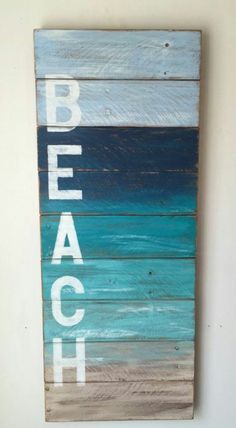 a wooden sign that says beach hanging on the side of a white wall next to a toilet