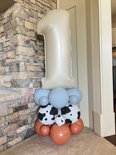 an inflatable number one balloon sitting on top of some brown and white balloons