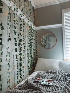 a bed with a blanket on top of it next to a window covered in christmas lights