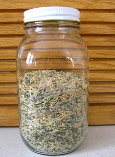 a jar filled with dried herbs sitting on top of a counter next to a wooden wall