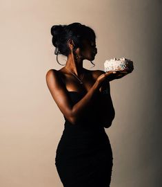 a woman in a black dress holding a cake