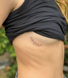 a woman's lower back with a small tattoo on her left side ribcage