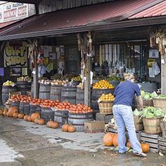 a man standing in front of a store filled with lots of fruits and veggies