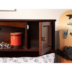 a wooden shelf with an orange bucket and snowboard on it next to a bed