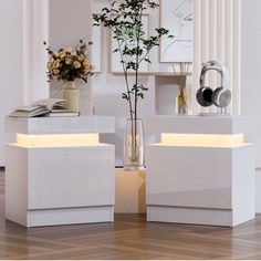 two white tables with flowers and headphones on them in front of a wall mounted mirror