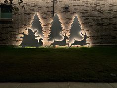 lighted christmas trees and reindeers in front of a brick wall