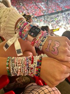 two people wearing bracelets with the number thirteen on their wrist and one holding an apple watch