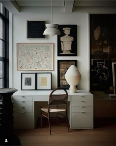 a room with many pictures on the wall and a chair in front of a desk