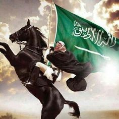 a man riding on the back of a black horse next to a green and white flag