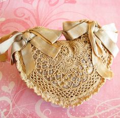 an old doily with bows on it sitting on a pink surface