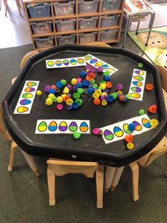 a black table topped with lots of different colored candies on top of wooden chairs