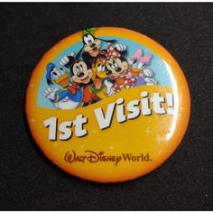 a button that says 1st visit with mickey mouse and other cartoon characters in the background